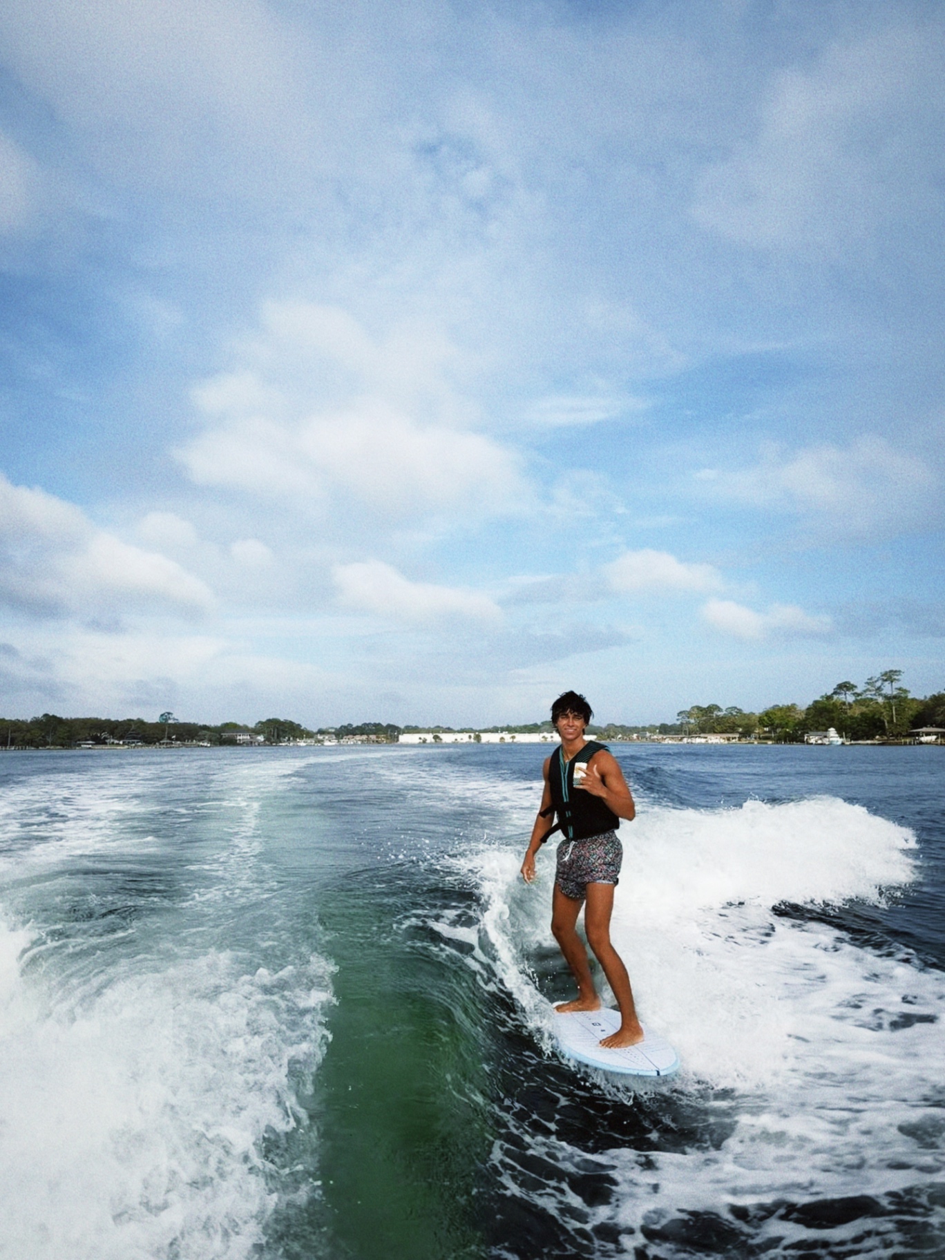 Wakesurfer smiling while riding the wave behind the Surf Bros boat