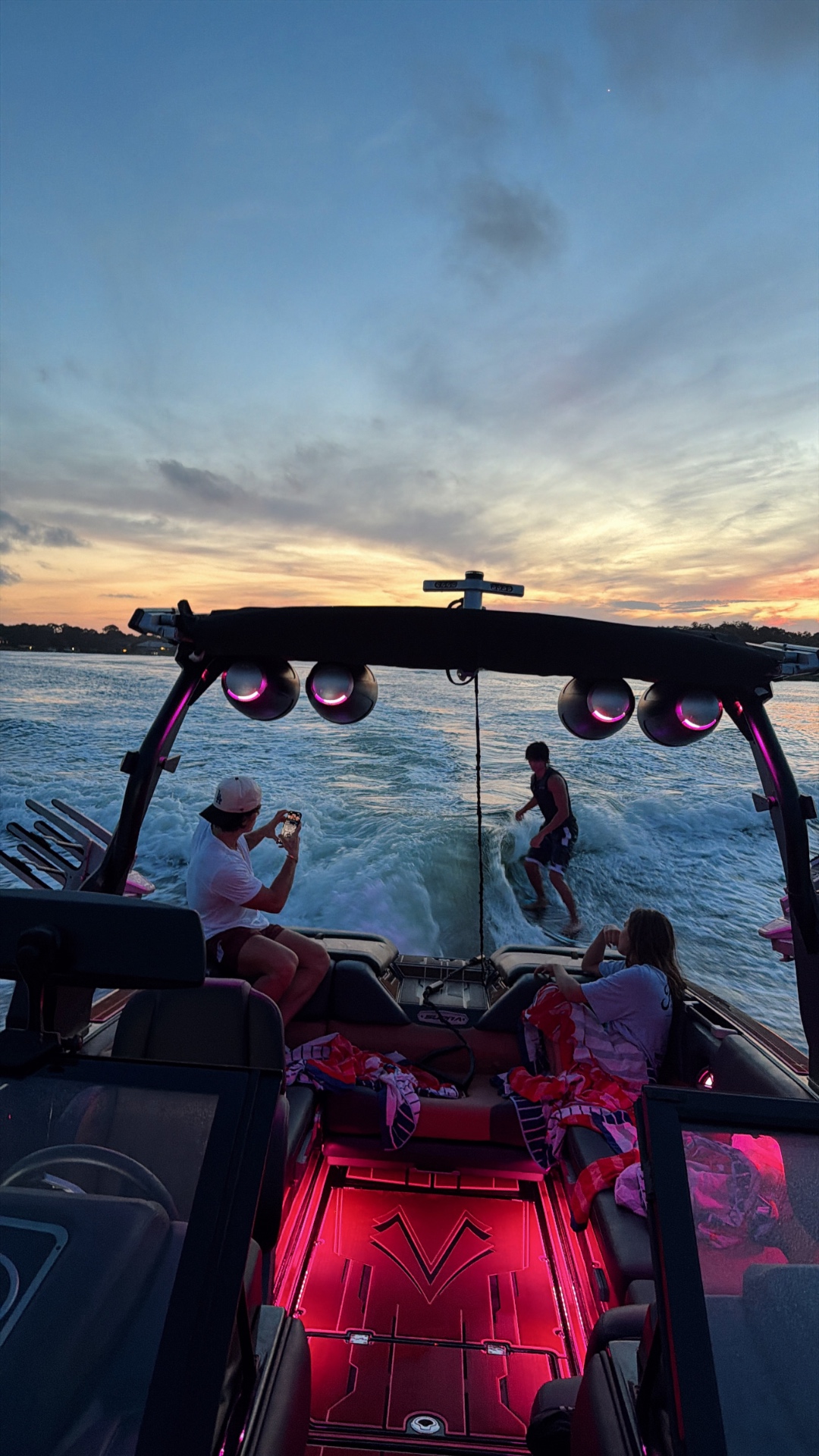 Sunset wakesurf run framed by pink tower lights and guests on board